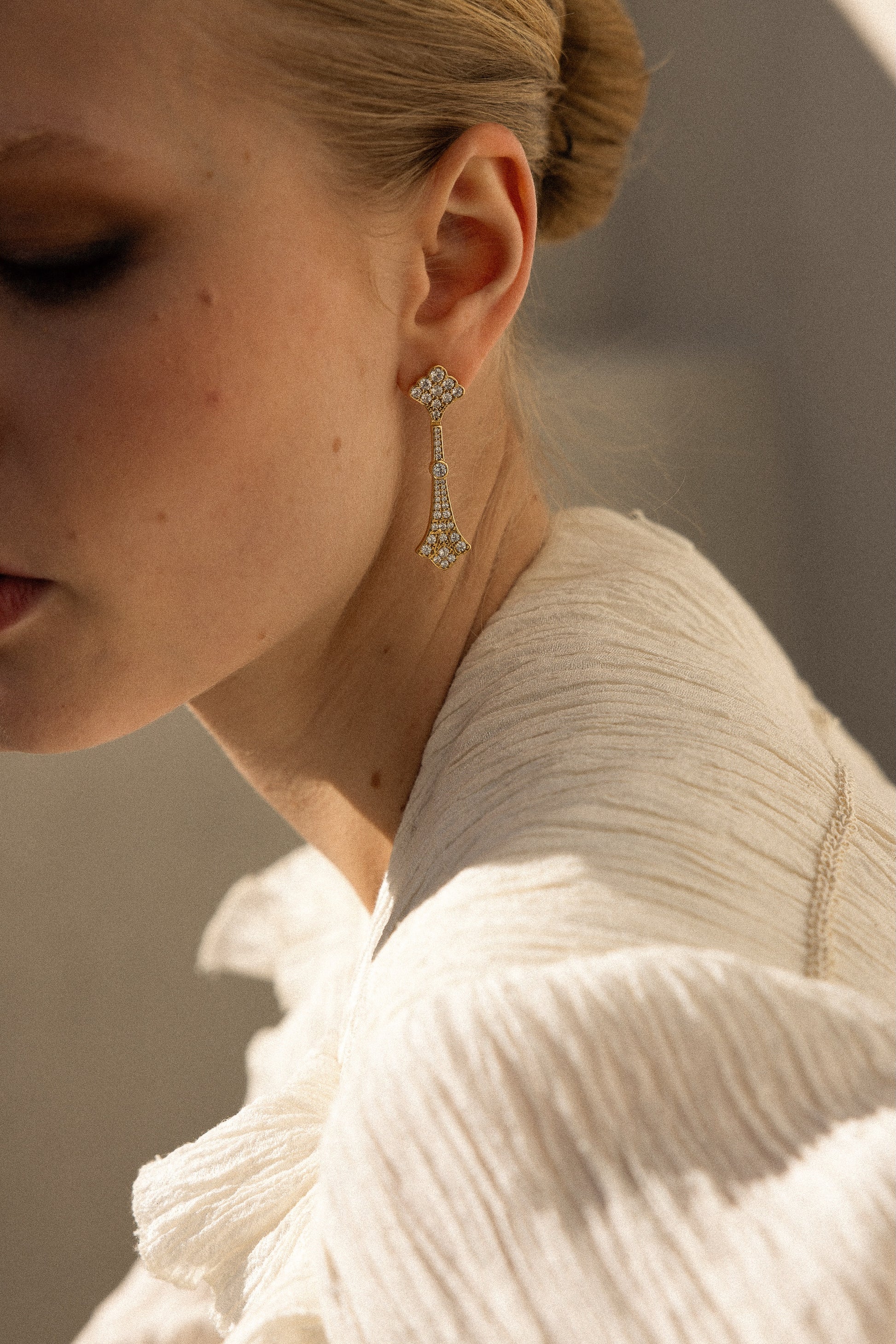Detalle de pendientes La Dame Oro dorados con circonitas engastadas y estructura geométrica alargada estilo Art Decó, joyas de novia SPREZZATURA