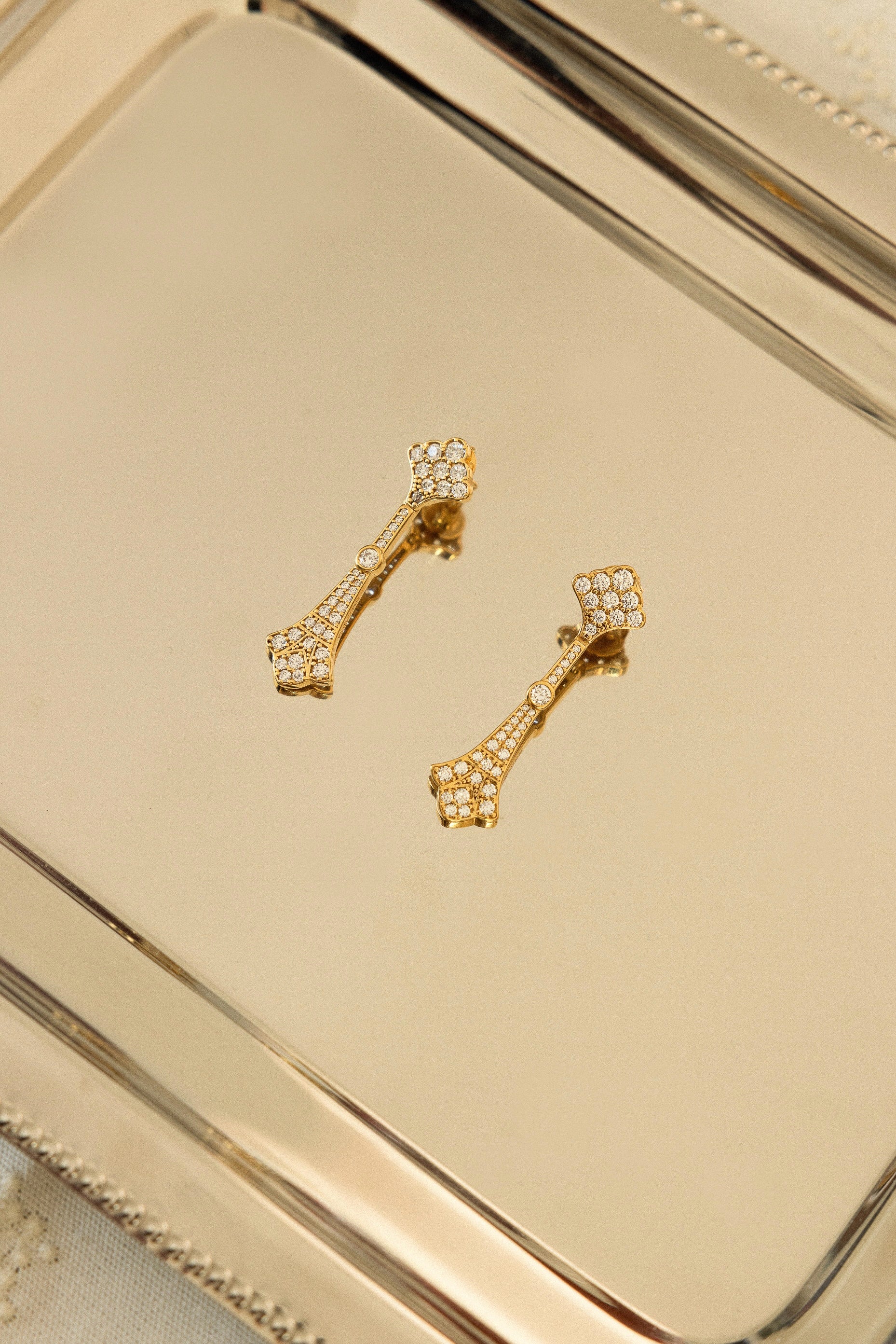 Pendientes La Dame Oro dorados con circonitas brillantes y diseño geométrico Art Decó sobre fondo neutro, joyas de novia SPREZZATURA